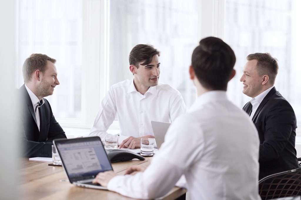 Geschäftstreffen mit vier Männern in einem hellen, modernen Büro, professionelle Atmosphäre.
