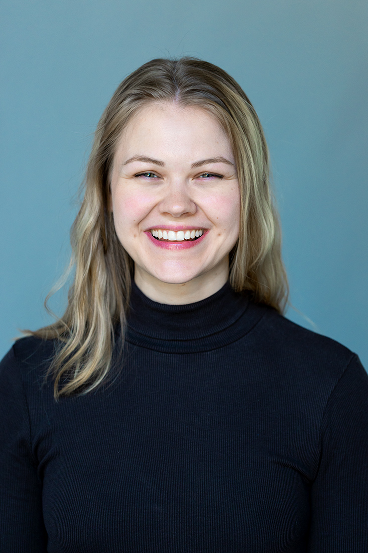 Lächelnde junge Frau im schwarzen Rollkragenpullover vor neutralem Hintergrund – professionelles Porträtfoto für Schauspielerin und Business-Profile