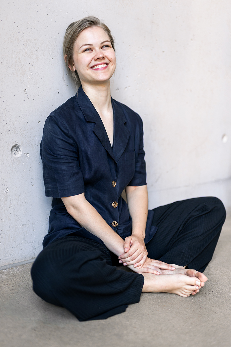 Lächelnde junge Frau im dunkelblauen Hemd vor neutralem Hintergrund – professionelles Porträtfoto für Schauspielerin und Business-Profile