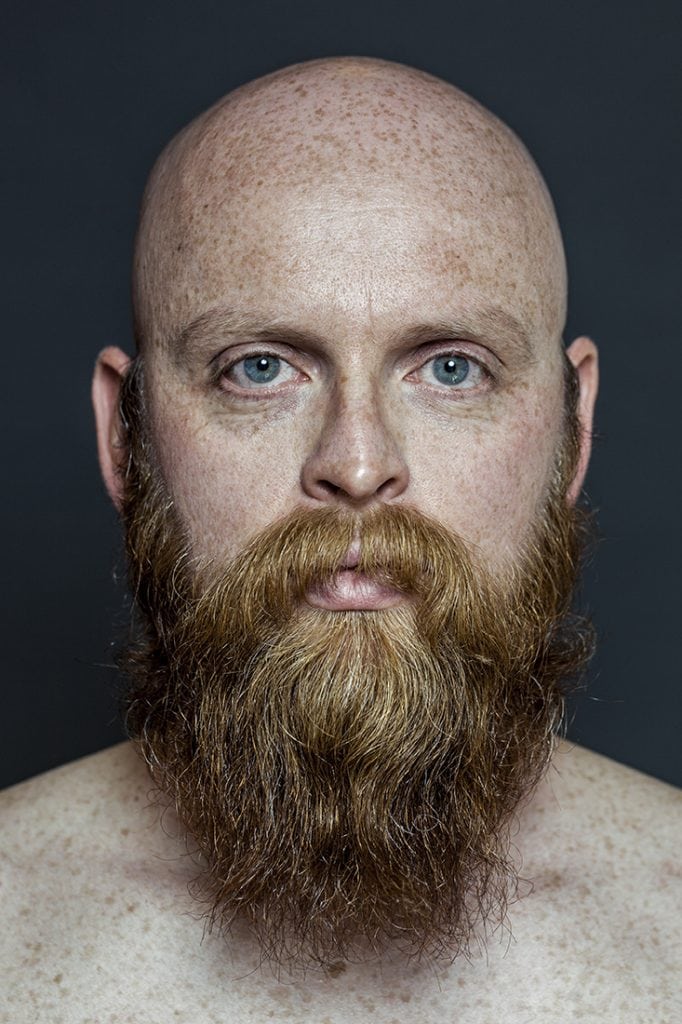 Nahaufnahme eines Mannes mit rotem Bart und blauen Augen, professionelle Fotografie.