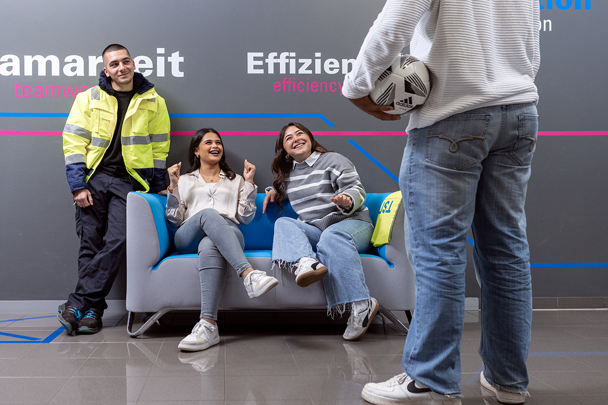 Junge Mitarbeiterinnen und Mitarbeiter entspannen im Lounge-Bereich eines modernen Unternehmens – Fokus auf Teamarbeit und Gemeinschaft