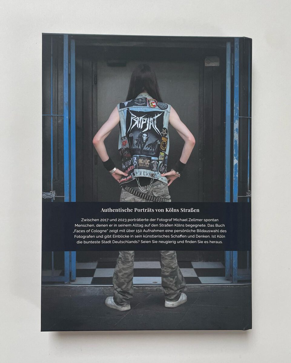 Die Buchrückseite des Fotobuchs "streetportrait faces of cologne" von Michael Zellmer, die ein Ganzkörperporträt einer Person von hinten in Tarnhose und Jeansweste mit Patches zeigt, die in einem Hauseingang steht. Darunter ist ein Text mit Informationen zum Buchinhalt abgedruckt.
